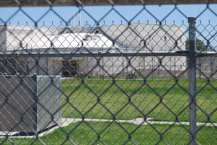 Image of an inmate in a wheelchair through a fence
